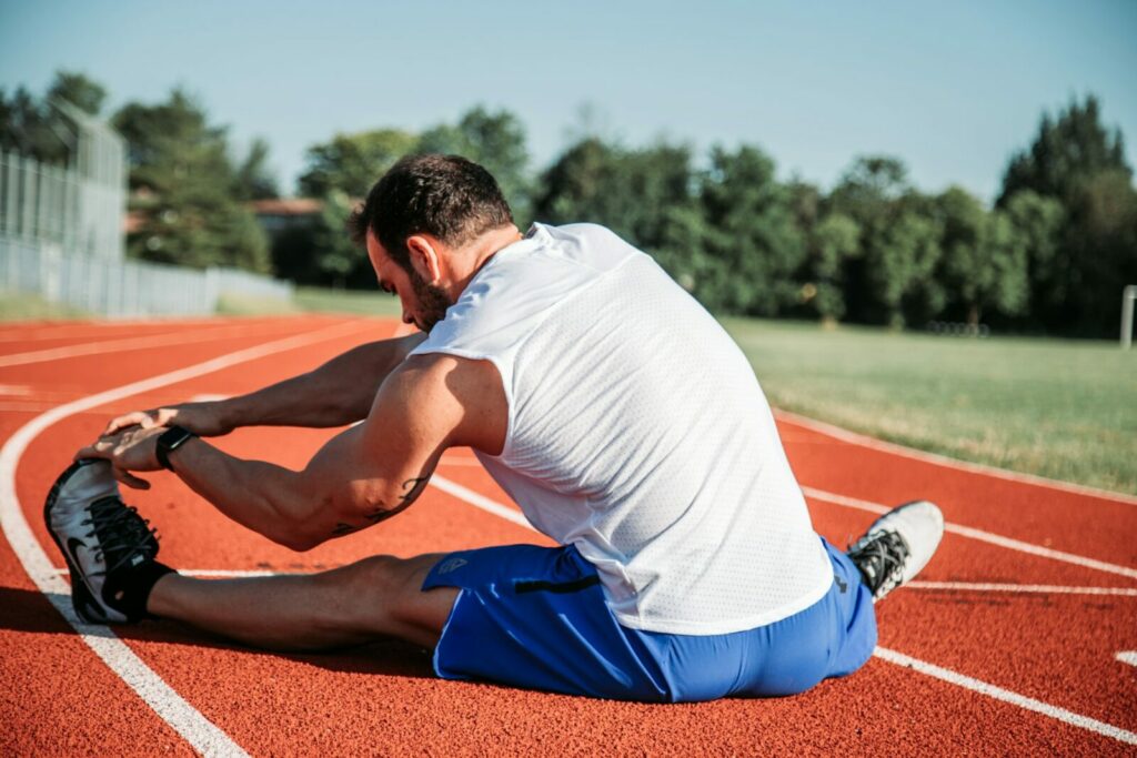 Sportif réalisant des étirements sur une piste d’athlétisme
